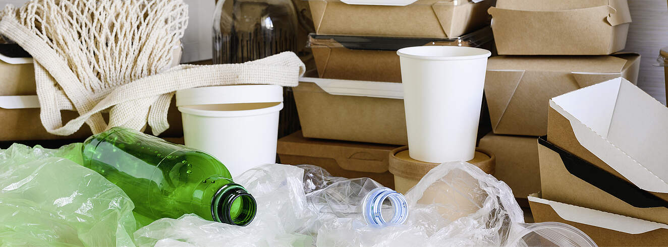 Nahaufnahme von Plastikmüll auf dem Küchentisch. Plastikmüll auf dem Hintergrund von Einweggeschirr aus Papier. - Foto (c) Nikita Burdenkov / iStock / Getty Images Plus
