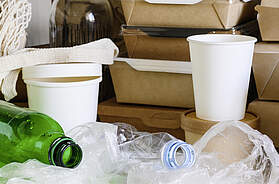 Nahaufnahme von Plastikmüll auf dem Küchentisch. Plastikmüll auf dem Hintergrund von Einweggeschirr aus Papier. - Foto (c) Nikita Burdenkov / iStock / Getty Images Plus