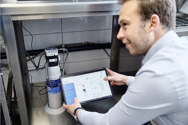 Marc-Pierre Jung, Sales Manager Digital Solutions DACH bei BRITA Professional Filter zeigt einem Kunden, wie die vom intelligenten Filterkopf PURITY C iQ gesammelten Daten im BRITA iQ Portal eingesehen werden können.