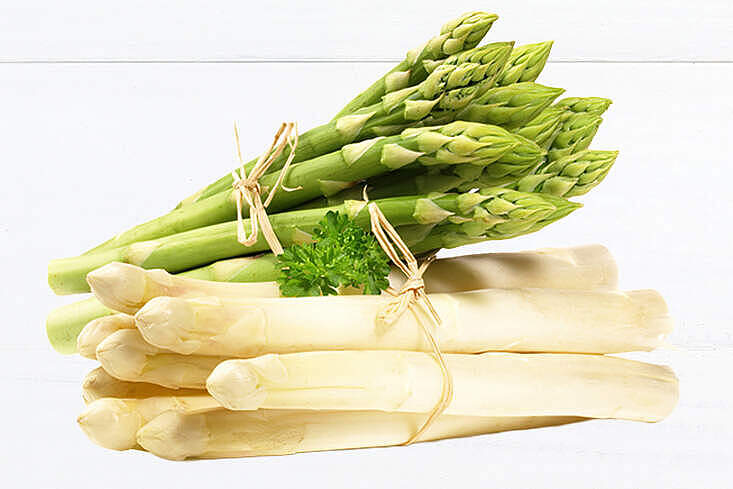 Bündel aus weißem und grünem Spargel auf heller Fläche, frisch geerntet und dekorativ angerichtet, symbolisch für die Frühlingssaison.