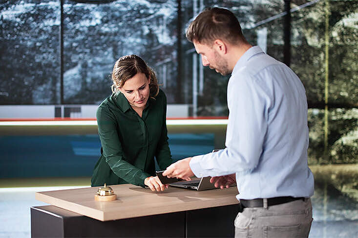 Hotelgast beim Check-in an einer Rezeption – die Mainzer Hotellerie kritisiert den zusätzlichen Aufwand durch die neue Bettensteuer.