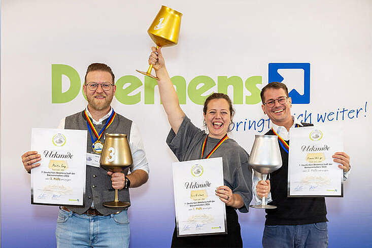 Die drei Erstplatzierten der Deutschen Meisterschaft der Biersommelièren und Biersommeliers 2026: Siegerin Iris Eickert, Zweitplatzierter Franz Uhlig (re.) und Drittplatzierter Martin Sorg