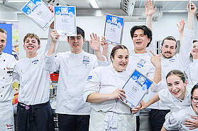 Die Finalisten des MILRAM Cup 2026 stehen gemeinsam mit Jury und Organisatoren nach der Siegerehrung auf der Bühne. Der Nachwuchs-Kochwettbewerb fand in Bremen statt.
