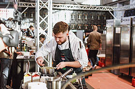 Mehrere Teilnehmer beim Finale des Wettbewerbs „Koch des Jahres“ 2025 während der Zubereitung ihrer Gerichte.