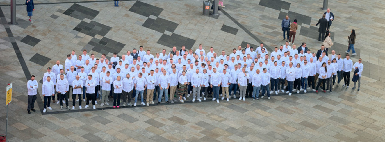 Großgruppe von Köchen und Gastronomievertretern beim JRE-Kongress 2026 in Köln, die gemeinsam für ein Gruppenfoto auf einem Platz posieren