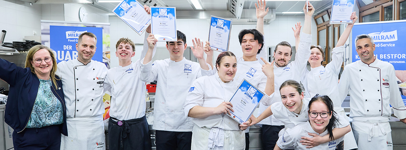 Die Finalisten des MILRAM Cup 2026 stehen gemeinsam mit Jury und Organisatoren nach der Siegerehrung auf der Bühne. Der Nachwuchs-Kochwettbewerb fand in Bremen statt.